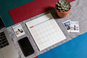 Small business owner planning monthly social media content calendar on a laptop with phone and notepad showing post drafts
